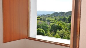 Ein Zimmer mit Fenster und Blick auf eine grüne Landschaft mit Bäumen und Häusern.