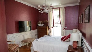 A bedroom with a large bed, a television, a dresser, and a chair.