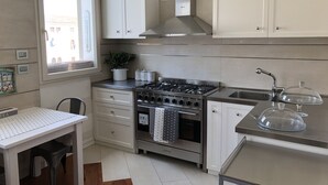 A modern kitchen with white cabinets, a stainless steel stove, and a window with a view of buildings.