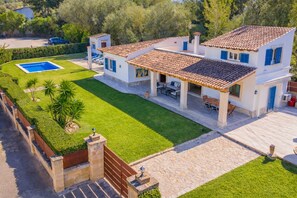 Une maison à deux étages avec une piscine, une terrasse et une pelouse bien entretenue.
