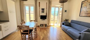 A spacious living area with a dining table, sofa, and a TV.