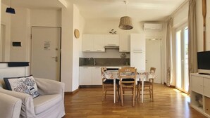 Un espacio habitable compacto con kitchenette, comedor, televisor y sofá.
