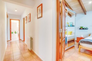 A hallway leading to a bedroom with a bed, bedside table, and a shelf with plants. - PORXET In the heart of the island, an oasis of peace with a swimming pool for 6 (Inca)