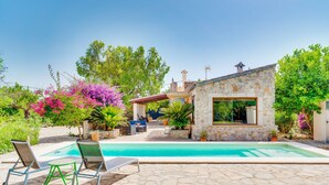 Une maison en pierre avec une piscine, du mobilier d’extérieur et une végétation luxuriante.