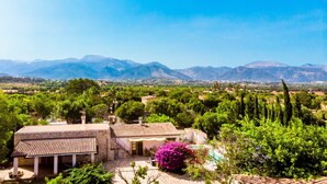 Une villa dotée d’un toit en tuiles, entourée d’une végétation luxuriante et offrant une vue sur des montagnes lointaines.