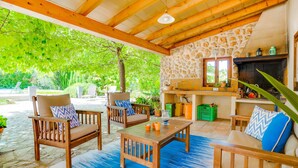 Une terrasse extérieure avec des meubles en bois, un mur en pierre et une cheminée en pierre.