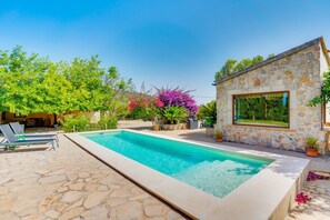 A swimming pool with stone tiles, a stone building with a large window, and lush greenery. - PORXET In the heart of the island, an oasis of peace with a swimming pool for 6 (Inca)
