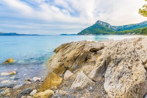 Uma costa rochosa com águas cristalinas e montanhas ao longe.
