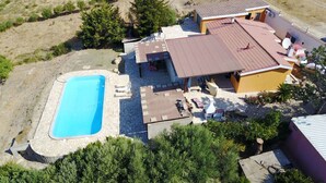 Ein Luftbild eines Hauses mit Schwimmbad, Terrasse und kleinem Garten.