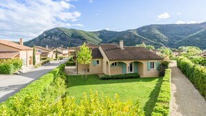 A residential area with houses, a well-maintained lawn, and mountains in the background. - Delightful villa for 4 people at Domaine Les Rives de l'Ardèche (Vallon-Pont-d'Arc)