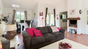 A living room with a sofa, a dining table, and a fireplace. - Delightful villa for 4 people at Domaine Les Rives de l'Ardèche (Vallon-Pont-d'Arc)