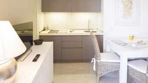 Une cuisine compacte avec un évier, un coin repas doté d’une chaise en osier et une carte accrochée au mur.
