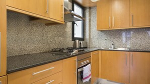 A kitchen with granite countertops, wooden cabinets, a stainless steel sink, and a gas stove.