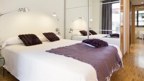 A modern hotel room with a large bed, multiple bedside lamps, and a large mirror.