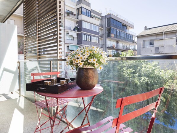 Ein Balkon mit Tisch, Stühlen, einem Blumentopf und einer Kaffeetasse-Serviertablett.