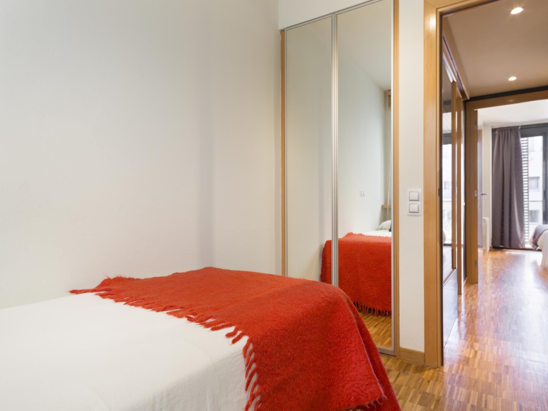 Ein Hotelzimmer mit Bett, großem Spiegel und Blick auf den Flur.