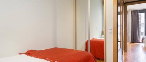 Habitación de hotel con cama, un espejo grande y vista al pasillo.