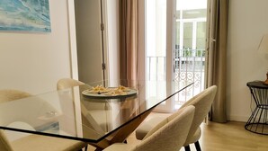 Et spiseområde med et glasbord, beige stole og en tallerken mad.