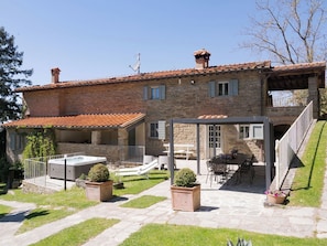 Une maison en pierre dotée d’un patio, d’un espace salon extérieur et d’un jacuzzi.