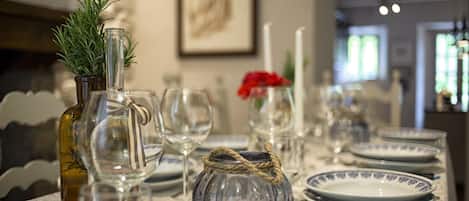 Une table à manger dressée avec de la vaisselle en verre transparent, une bougie et un vase décoratif.