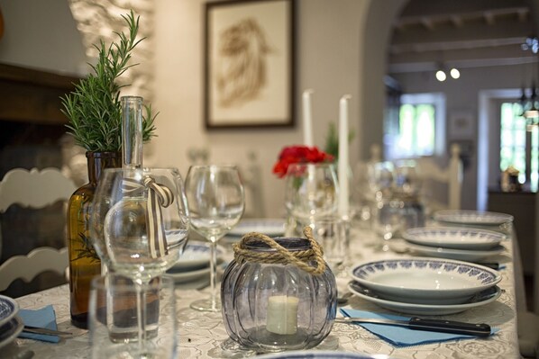 A dining table set with clear glassware, a candle, and a decorative jar.