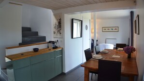 A modern kitchen with a wooden countertop and green cabinets, a dining area with a wooden table and chairs, and a staircase leading to another level. - La Maison de l'Aber, at the edge of Aber Wrach, sea view (Landéda)