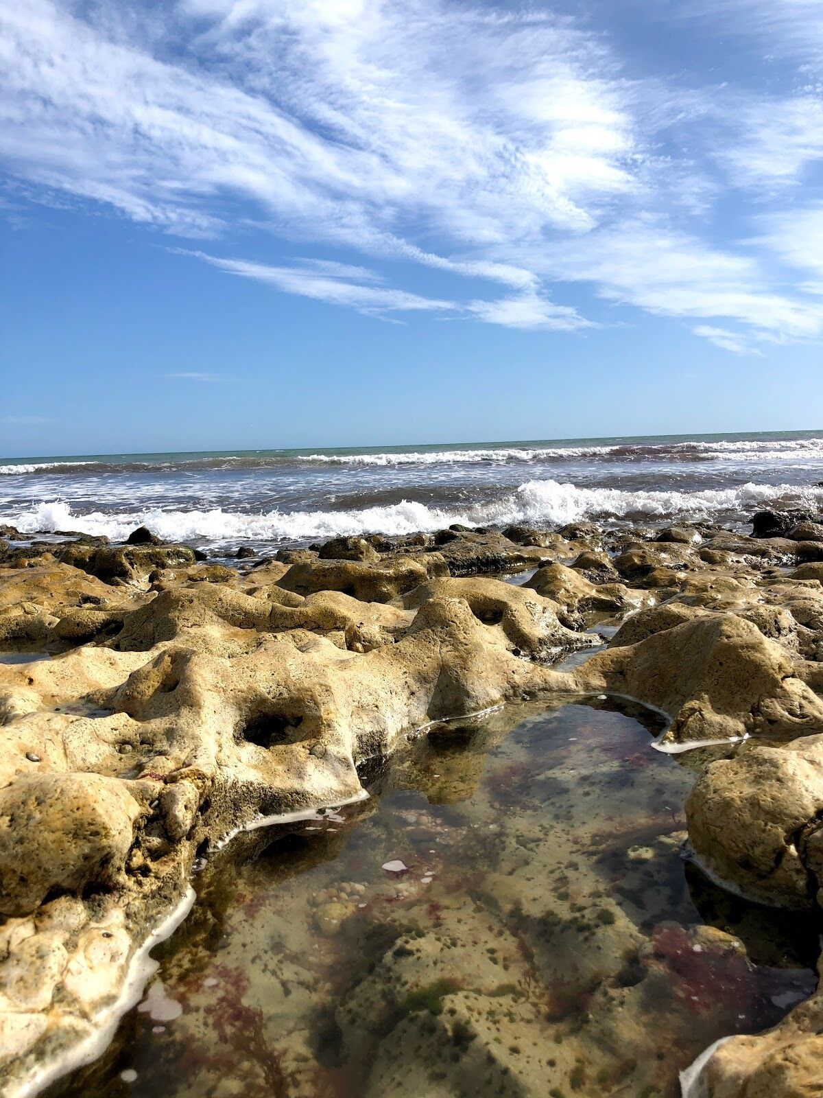 Una platja rocosa amb onades que brollen a la riba.