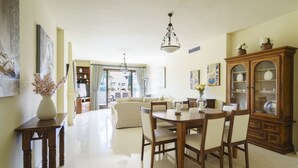 Un salon spacieux avec un coin repas, un grand meuble en bois et une vue à travers une porte vitrée.