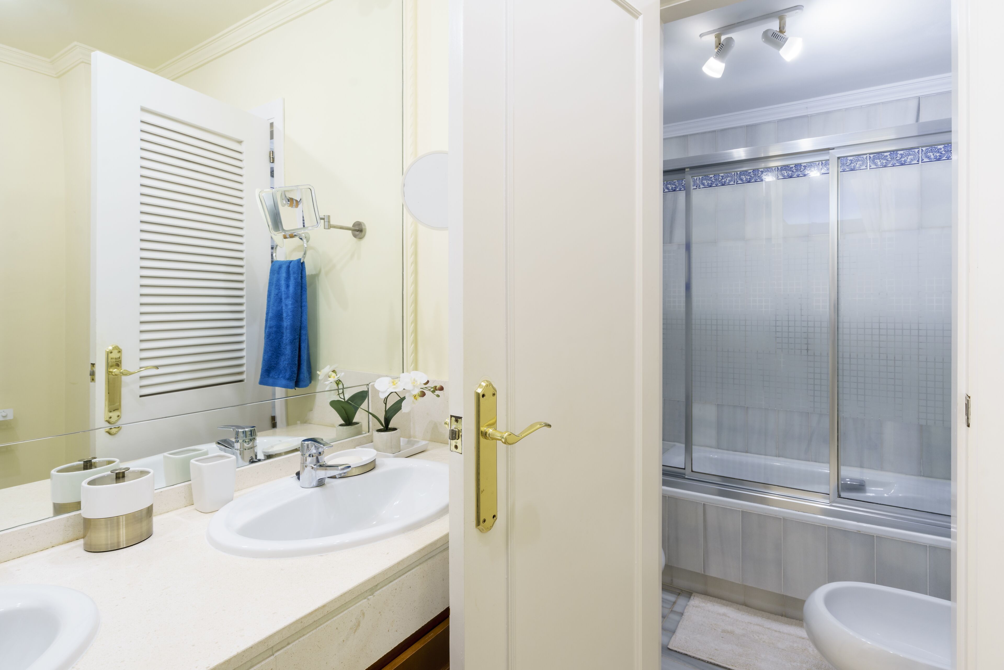 A bathroom with a white sink, a mirror, and a shower area.
