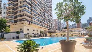 A swimming pool with lounge chairs and potted plants, surrounded by high-rise buildings. - Acuarium 3-19-E (Benidorm)