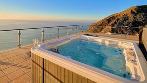 A hot tub with a view of the ocean, a wooden deck, and a railing. - Quinta Pereira ... beautiful panoramic views and ocean sunsets  (Faja Da Ovelha)