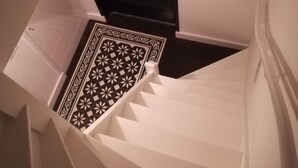 Una escalera con paredes blancas y un suelo con estampado blanco y negro.