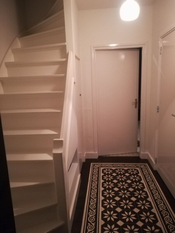 Un escalier menant à une porte, devant laquelle se trouve un tapis à motifs.