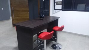 Una zona de bar con un mostrador de madera oscura y dos taburetes rojos.