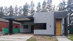 Una casa moderna de dos plantas con techo plano, ventanas amplias y una puerta de madera.