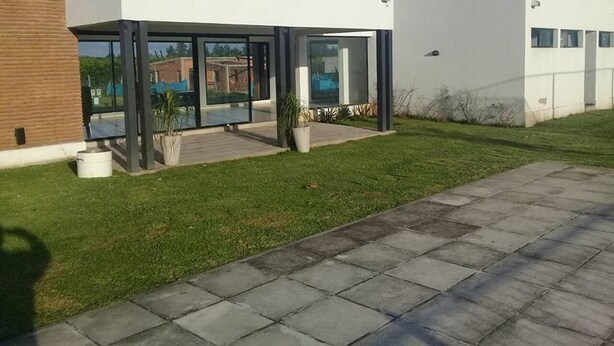 Una casa moderna de dos pisos con grandes ventanales, techo plano y entrada pavimentada.
