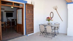 A room with a wooden door, a table with chairs, a vase with flowers, and a pitchfork on the wall. - CAN PERE Authentic country house with a pool, just 6 km from the nearest beach (Sant Joan de Labritja)