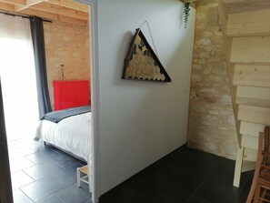 Une chambre à coucher comprenant un lit, un petit tabouret, une armoire rouge et un élément décoratif mural.