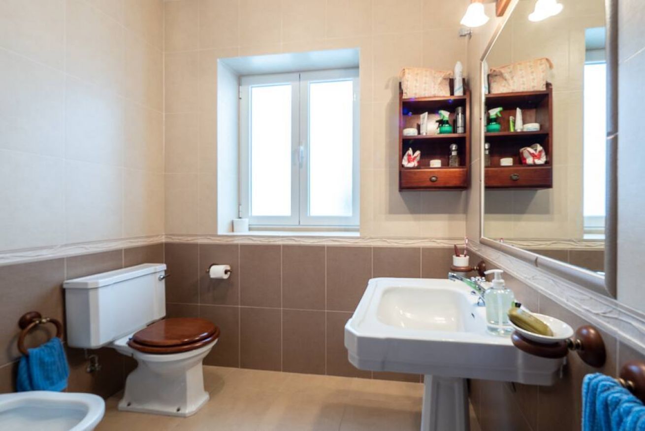 A bathroom with a toilet, bidet, sink, and a window.