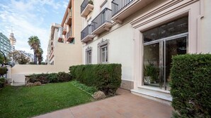 Un edificio moderno con un giardino curato, ampie finestre e un'area d'ingresso pulita e con piastrelle.