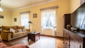 Un soggiorno con divano, tavolino, mobile TV e finestra con tende.