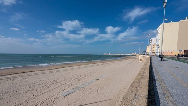 Una spiaggia con una passeggiata lastricata e edifici sullo sfondo.