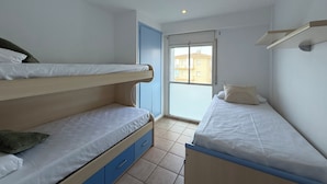 Een kleine, lichte kamer met twee stapelbedden, een raam en een deur.