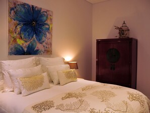 A bedroom with a bed, pillows, a lamp, a cabinet, and a painting. - Fully equipped air-conditioned apartment in central Setúbal (Setúbal)