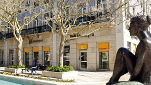 A bronze sculpture of a seated figure in an outdoor plaza with a pool, surrounded by buildings with storefronts and balconies. - Fully equipped air-conditioned apartment in central Setúbal (Setúbal)