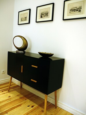 A black console table with a bowl and a circular object on top, flanked by three framed photographs on the wall.