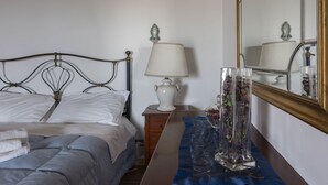 A neatly made bed with white linens, a bedside table with a lamp, and a mirror on the wall. - Apartment in two-room villa called Lipari 4/5 beds (Reitano)