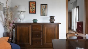 A dining area with a wooden table and chairs, a cabinet with decorative items, and a view into another room. - Apartment in two-room villa called Lipari 4/5 beds (Reitano)