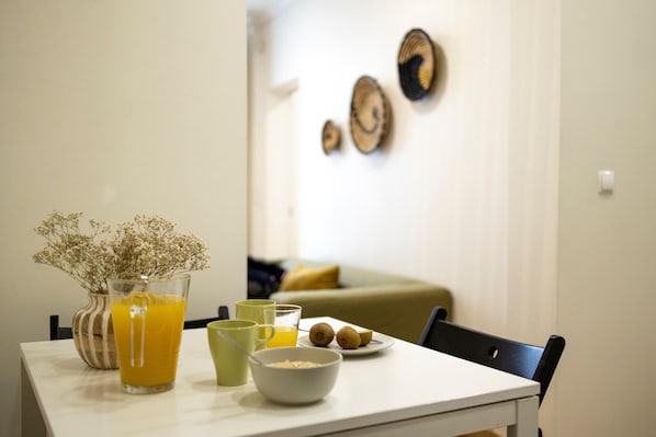 A dining table with a glass of orange juice, a bowl of cereal, and a plate with two kiwi fruits. - Comfortable apartment with two bedrooms, fully equipped, very close to the center of Lisbon in the traditional Alfama district. (Lisboa ciudad)
