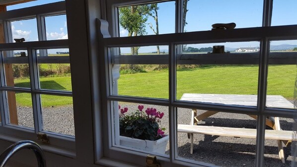 A window with a view of a grassy field and a wooden bench.
